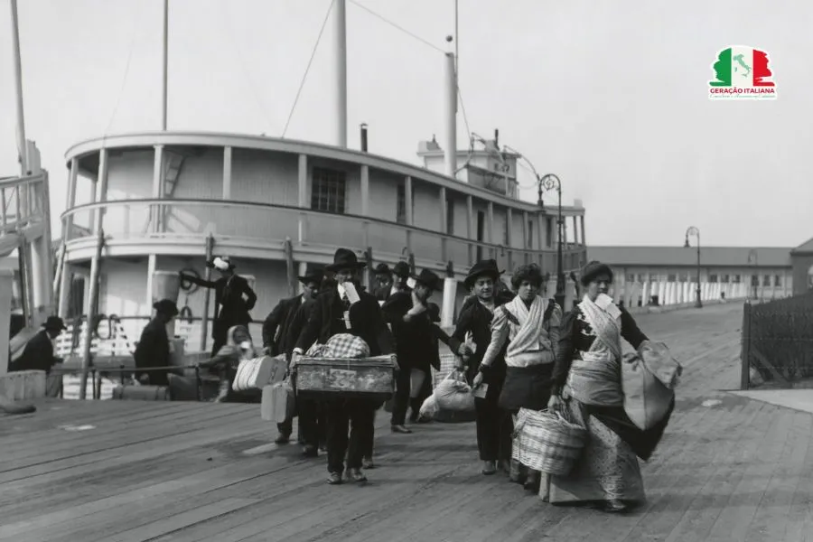 Imigrantes italianos desembarcando na Ilha Ellis, c. 1892-1910. Eles acabaram de sair de uma balsa que os transportou de seu transatlântico até a Estação de Imigração dos EUA para triagem de admissão. Alguns seguram o número de entrada nos dentes (BSLOC_2018_4_225)